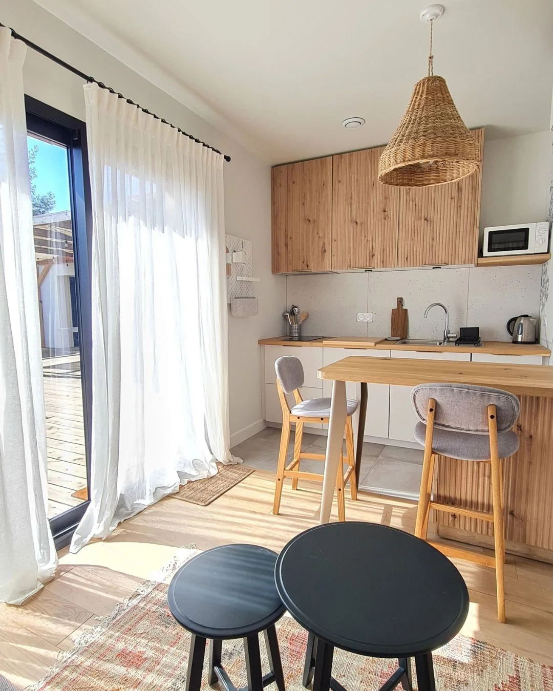 Rénovation d'un studio de 16m² à Saint-Médard-en-Jalles : espace de vie optimisé dans des tons chaleureux, parquet bois, tables gigognes, luminaire en osier