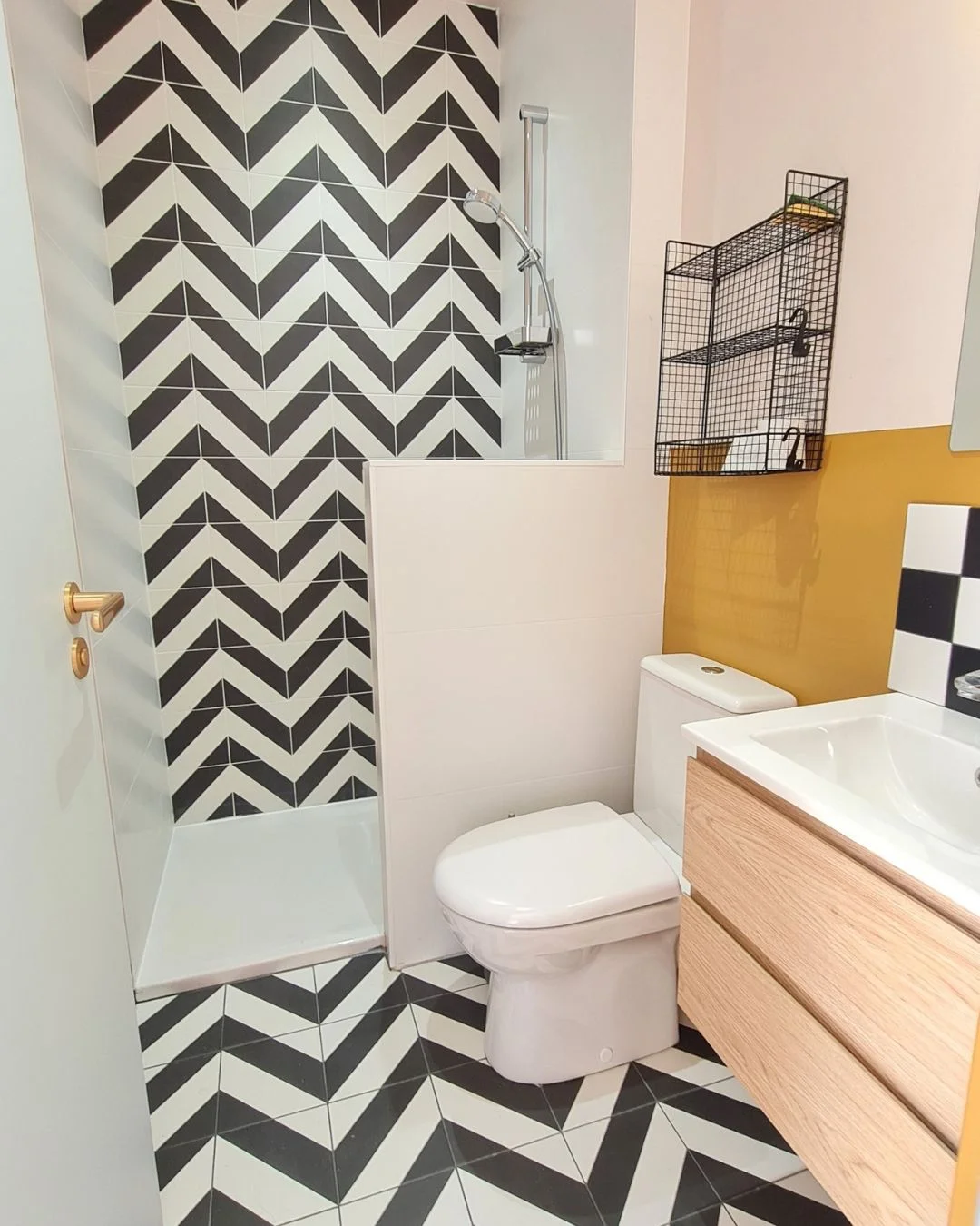 Rénovation d'un studio de 16m² à Saint-Médard-en-Jalles : salle de bain avec carrelage noir et blanc en point de Hongrie, mur jaune et rose clair, douche, wc et petit lavabo